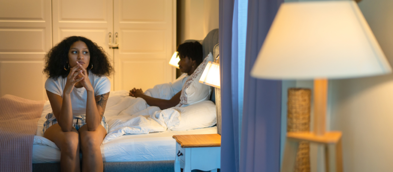 A woman sits on the bed with her toxic partner.