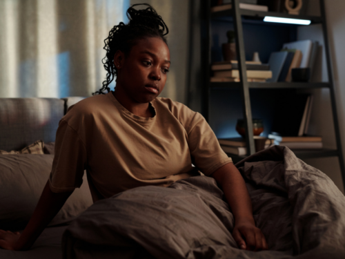 A woman sits in bed catastrophizing.