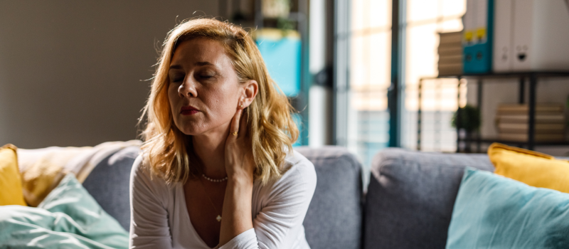 A woman sits on a couch with PMDD.