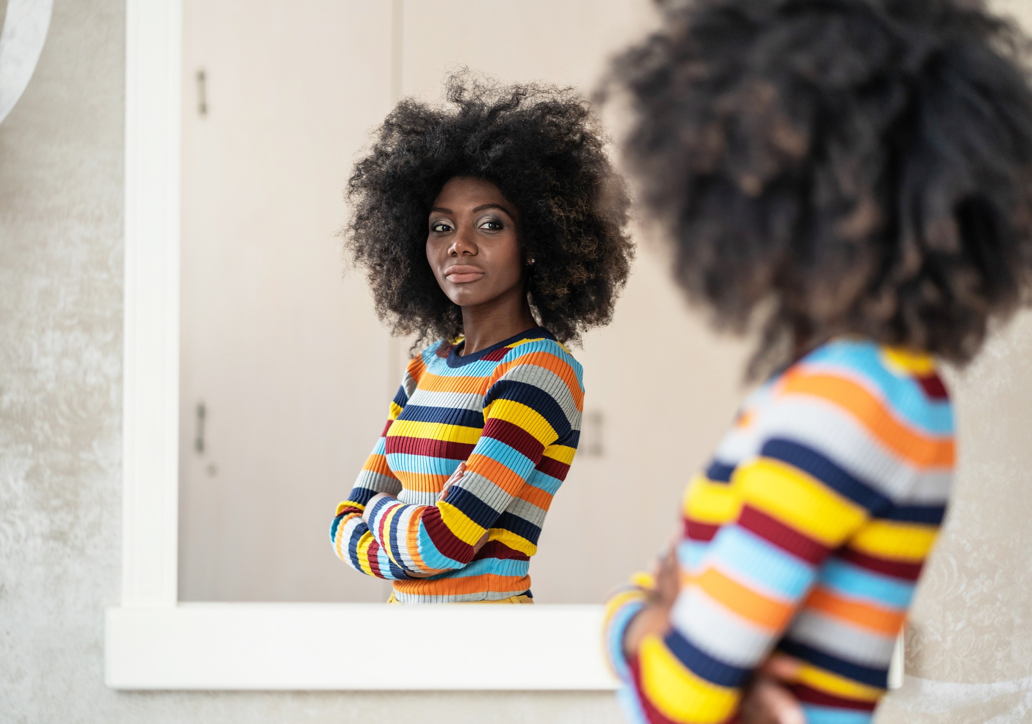 Afro Woman looking positively at her reflection in the mirror