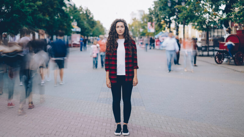 Woman stands frozen in the middle of a moving scene, representing her functional freezes due to her trauma.