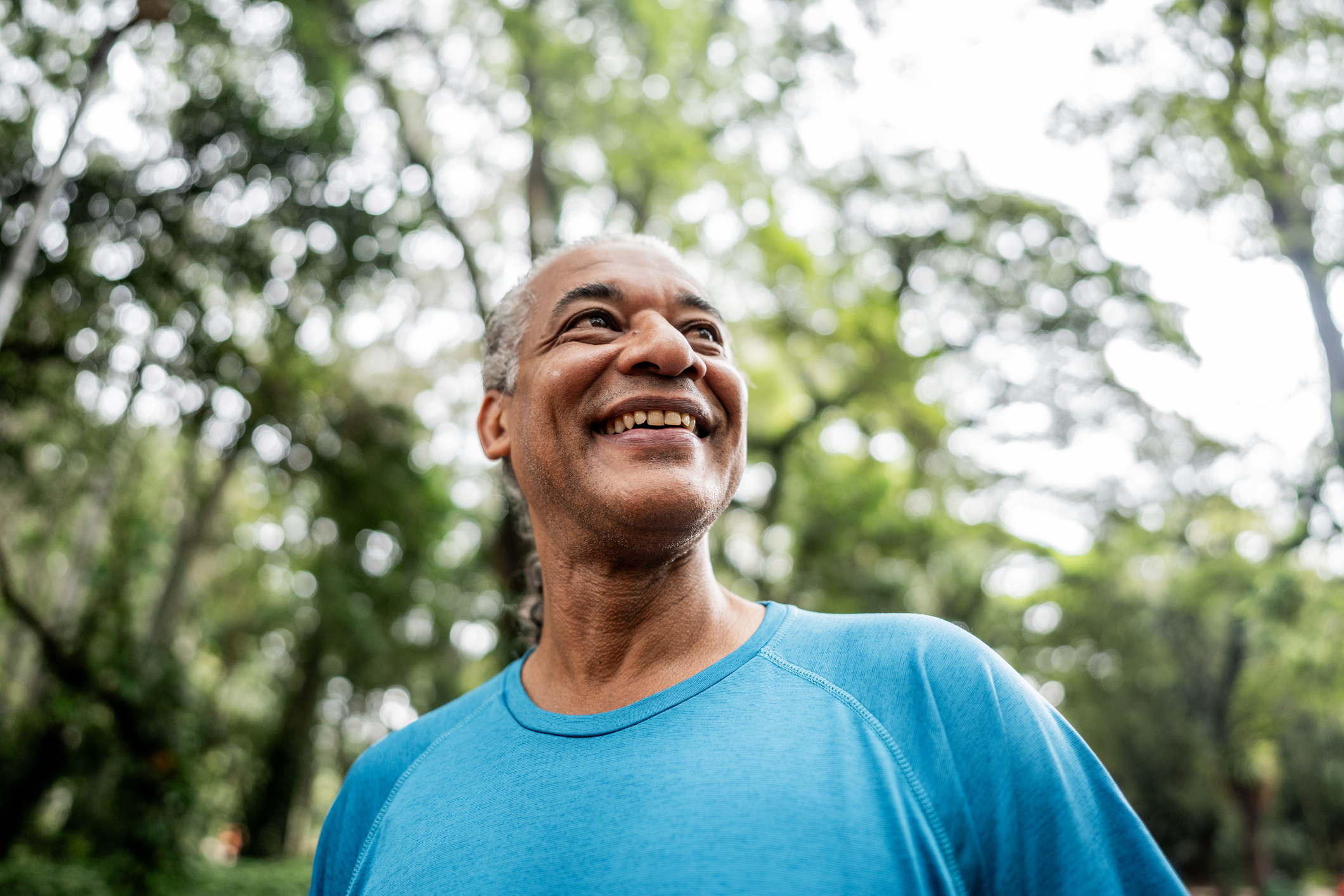 Senior man feeling happy in a public park as he is able to control his panic attacks.