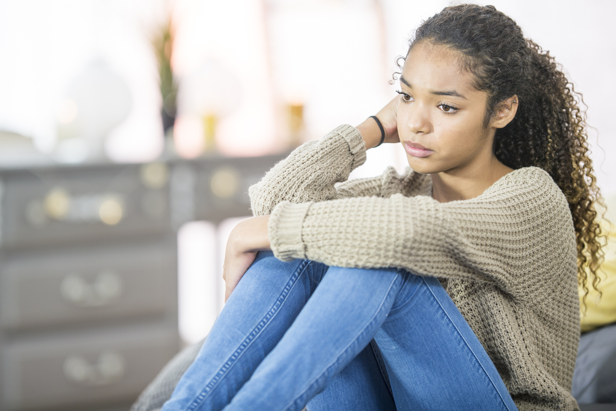 A teenage girl indoors in a bedroom feeling guilty about a decision she made.