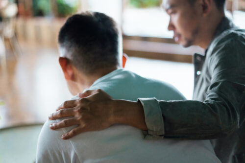 Father caring for his son who has psychosis, comforting and consoling him.