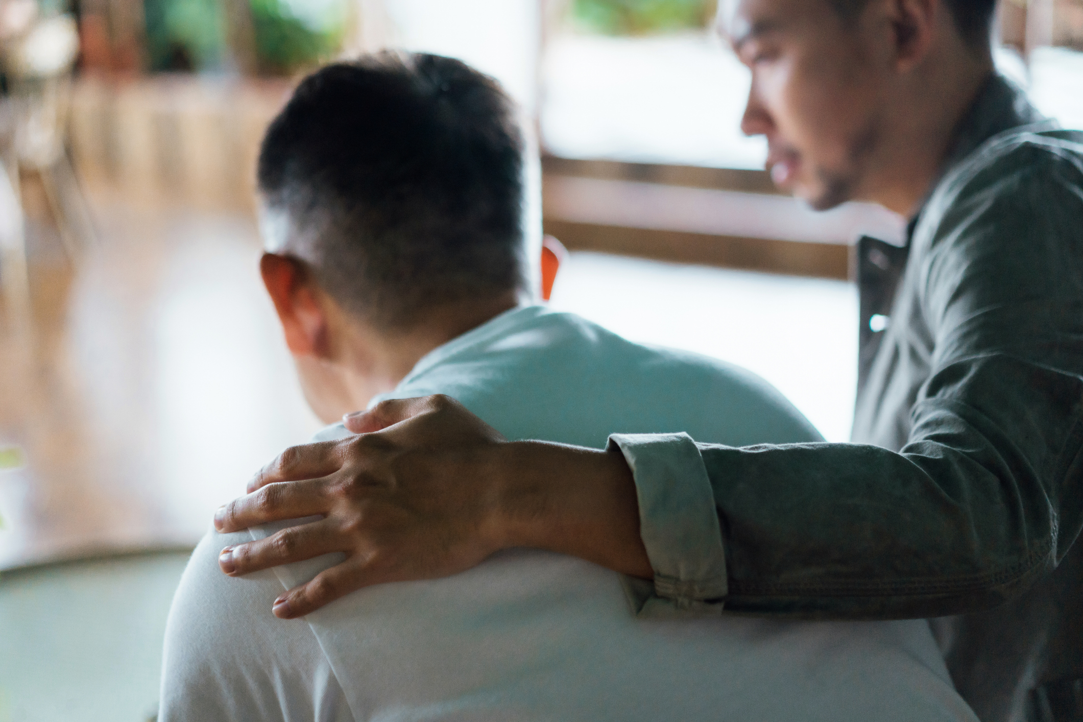 Father caring for his son who has psychosis, comforting and consoling him.