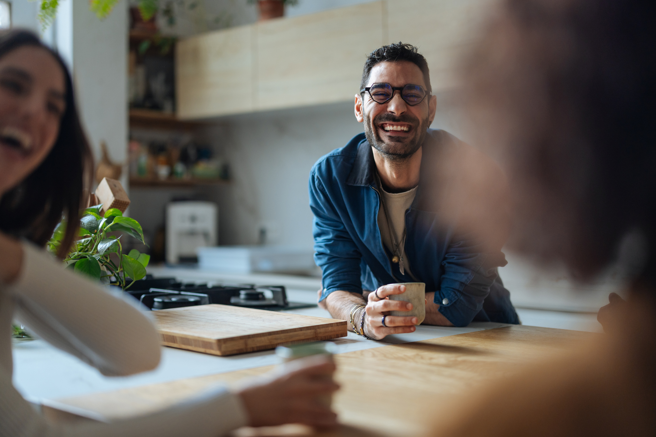 Group of friends enjoying a coffee break together in a modern kitchen, sharing laughter and good times without the thought of a vape.