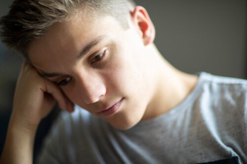 Young man feeling upset about his self-harm thoughts.