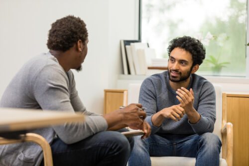 Young man explaining his recent exposure therapy process to his friend.