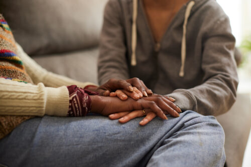 Close-up of two people holding hands in a comforting gesture, symbolizing emotional support and connection.