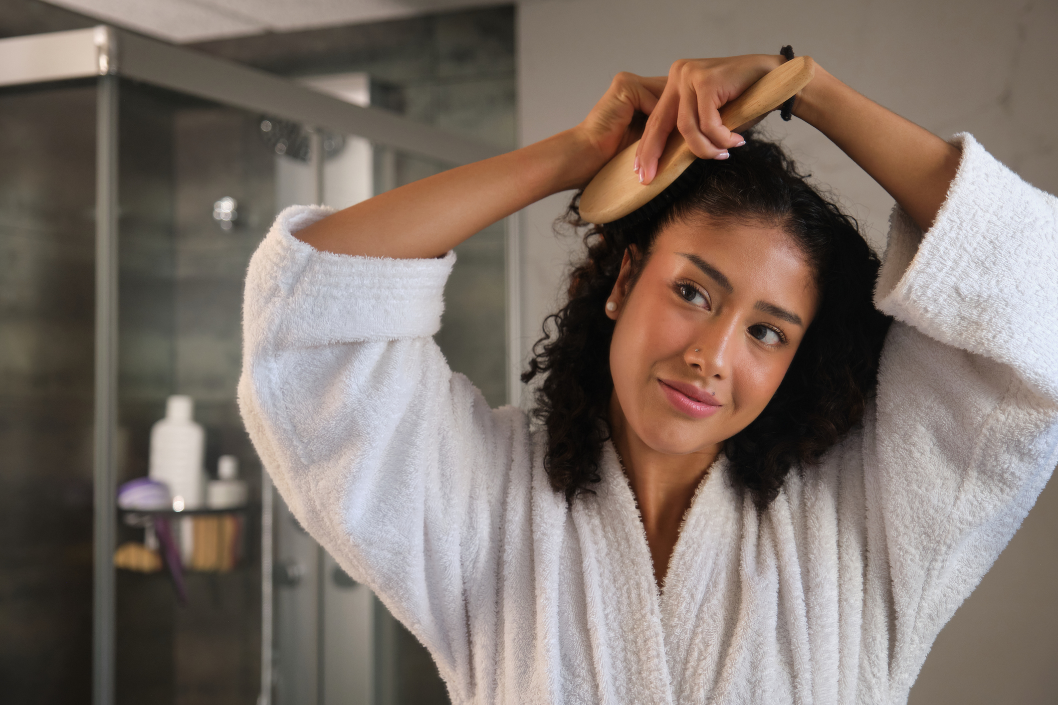 Young woman smiling in the mirror after figuring out her PMDD and having it under control.