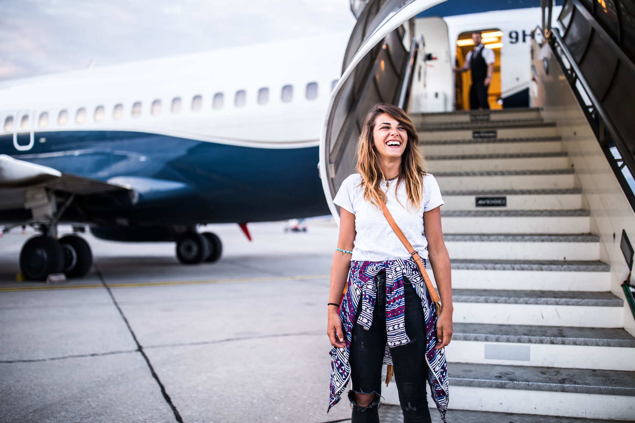 Smiling woman stepping off an airplane, appearing calm and relaxed—suggesting the positive effects of using medication to ease flight anxiety.