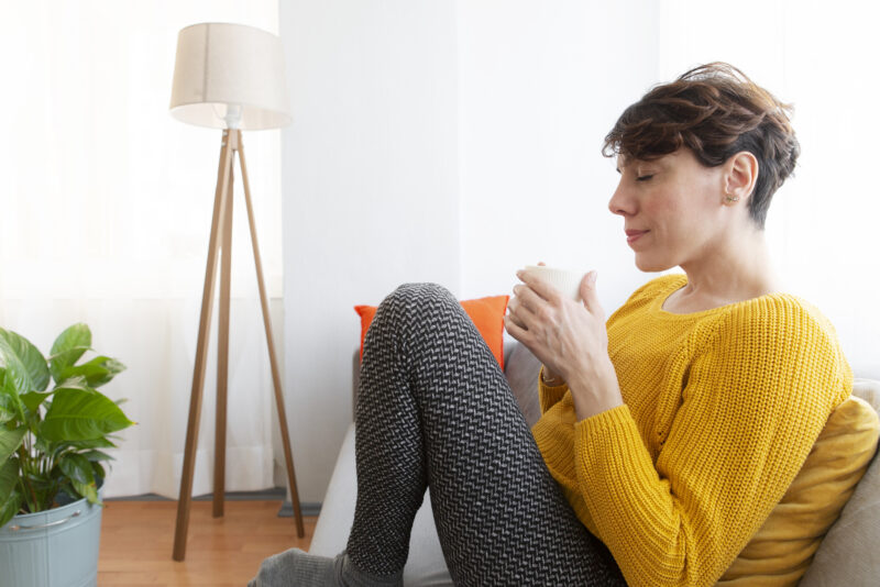Woman sitting calmly with a hot drink, symbolizing relief and emotional balance potentially supported by PMDD medication.