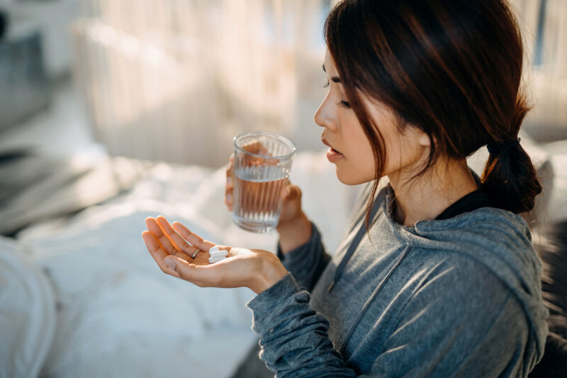 Woman holding prescription pills and a glass of water, representing the start of treatment for Xanax dependency.