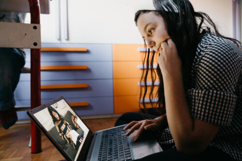 Teen girl engaging in a virtual therapy session on her laptop, illustrating the accessibility of holistic care through the biopsychosocial model.