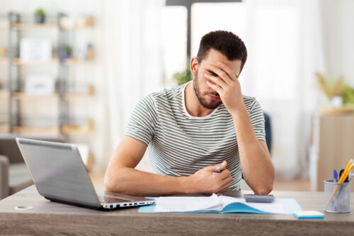 Young man overwhelmed while working at a desk, representing the mental fatigue and focus difficulties linked to executive functioning challenges.