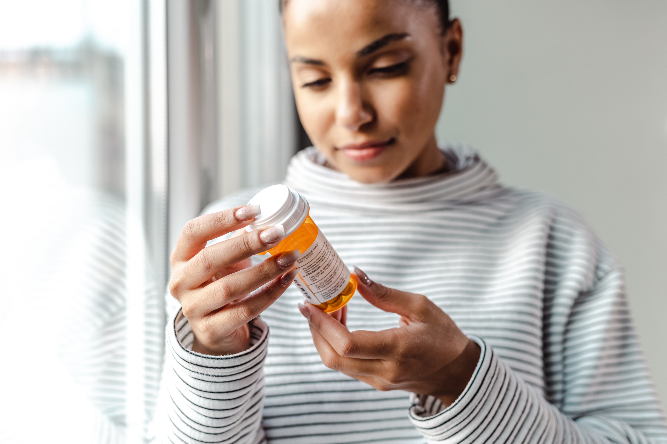 Woman carefully reading a prescription bottle, highlighting the importance of proper medication use during Xanax addiction recovery.
