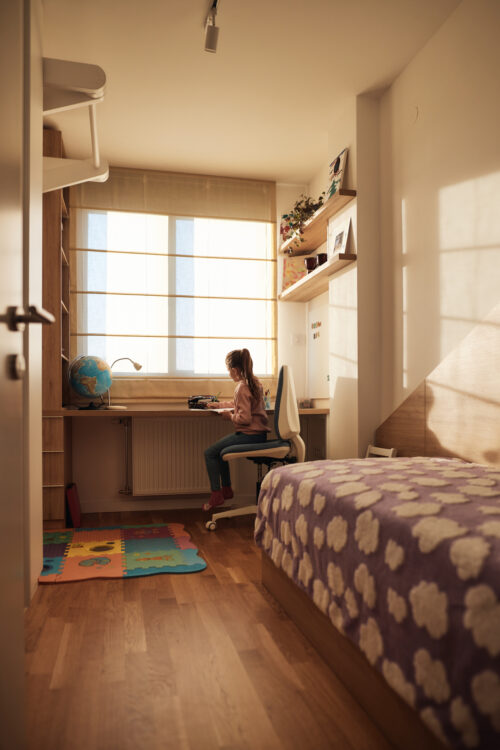 Young girl sitting alone at a tidy desk in her bedroom, reflecting the repetitive behaviors and need for order often associated with childhood OCD.
