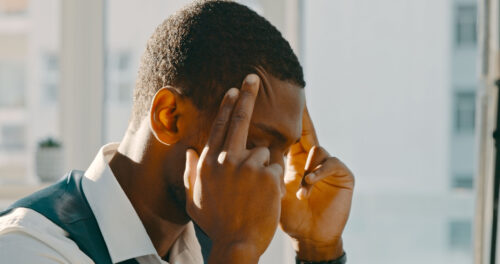 Man holding his temples with both hands, appearing overwhelmed or deep in thought, representing trauma-related memory loss.