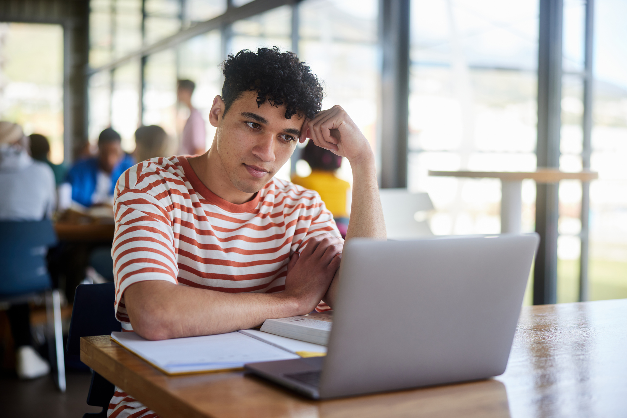 Student staring at laptop with a distracted expression, illustrating challenges with focus and attention often faced by people with ADHD.