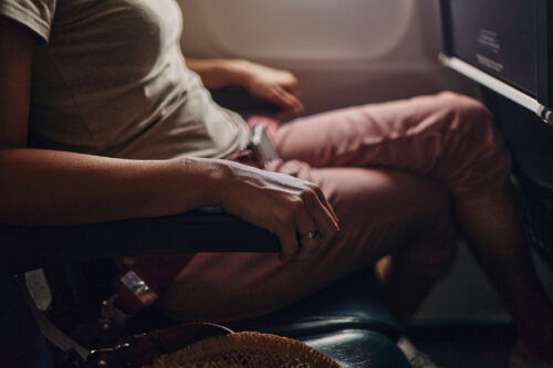 Close-up of a tense hand gripping an airplane armrest, symbolizing anxiety or nervousness during flight.
