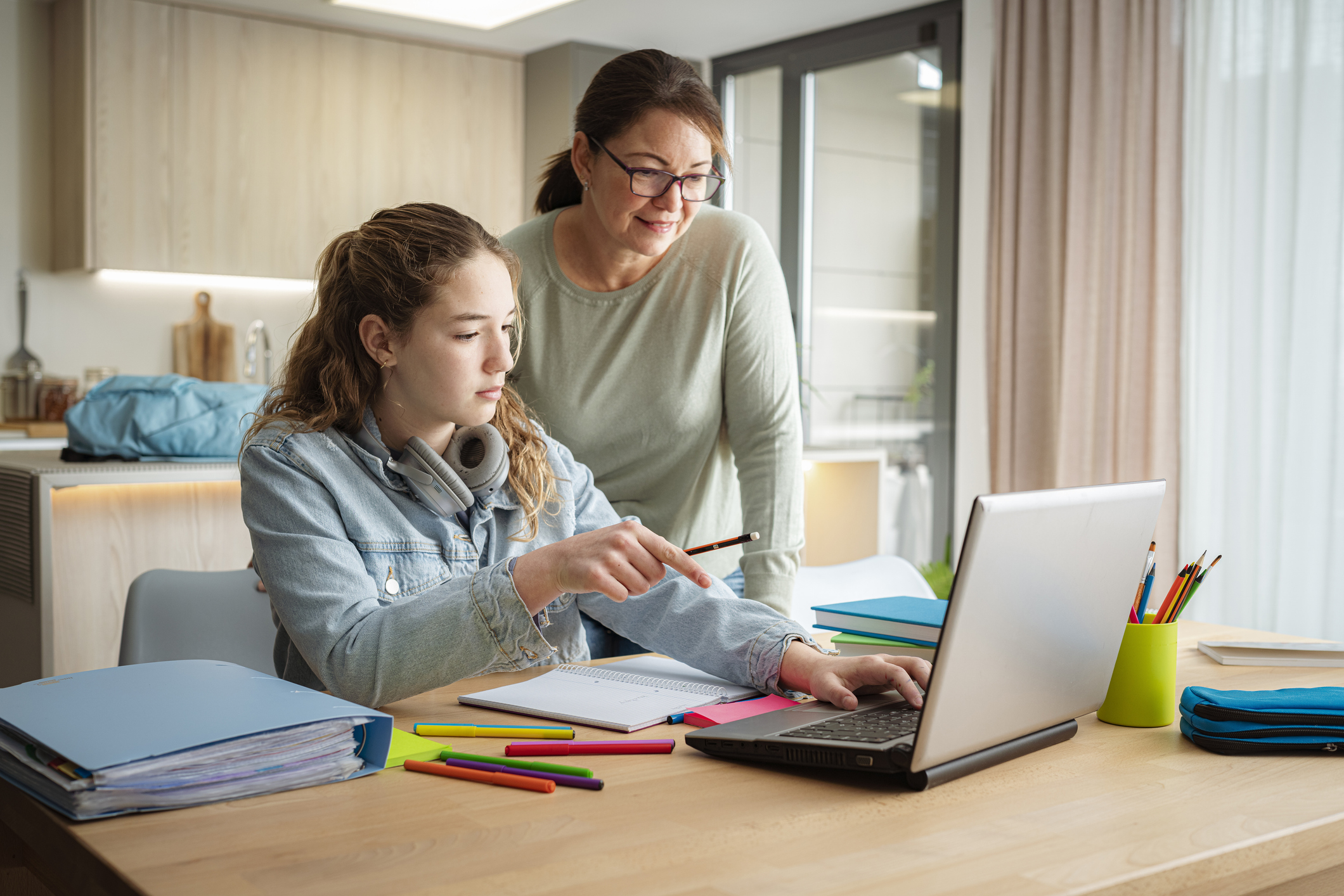 Teen girl working on a laptop with an adult offering guidance, illustrating the importance of support in developing executive functioning skills like planning and task management.