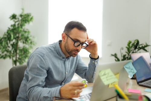 Adult man concentrating on work at his desk, showing the effort and tools used to stay focused while managing ADHD symptoms.