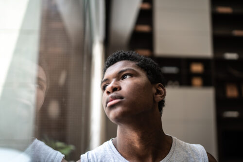 Teenager gazing out a window with a pensive expression, capturing the emotional toll and seriousness behind shocking eating disorder statistics.