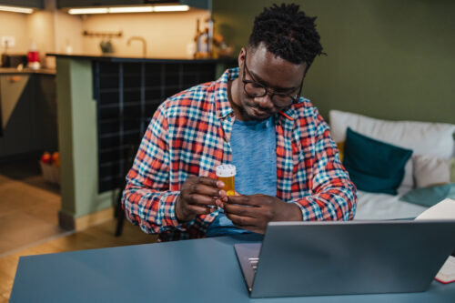 Man reading a prescription label at home, symbolizing attention to medication guidelines while taking low dose Naltrexone.