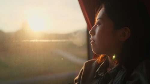 Woman gazing out window, reflecting on emotional progress and the recommended length of therapy.