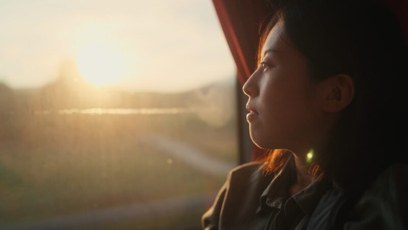 Woman gazing out window, reflecting on emotional progress and the recommended length of therapy.