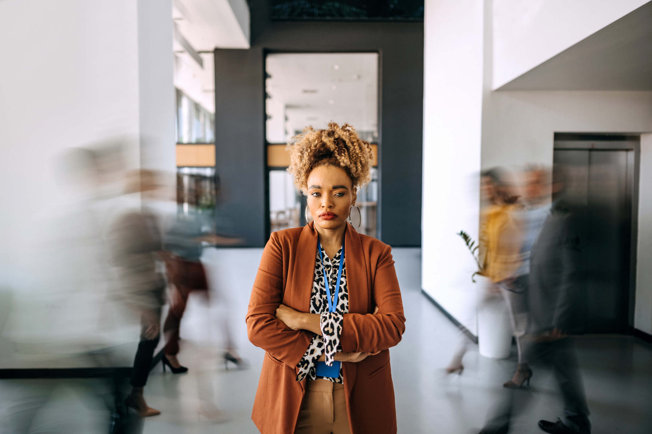 Woman with crossed arms in an office, showing resilience and strength despite mental health stigma.