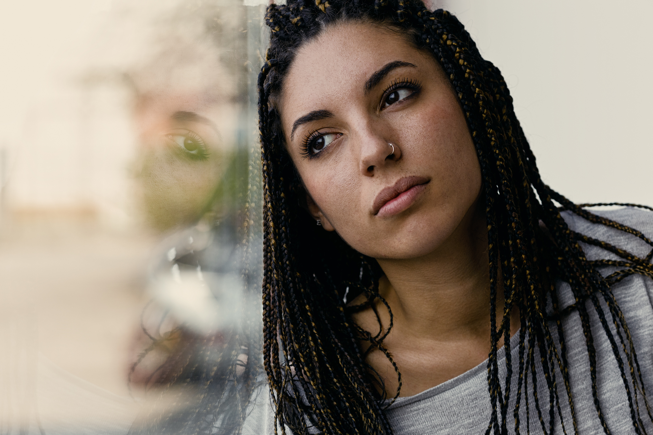 Woman looking out window thoughtfully, representing the complex connection between trauma and schizophrenia.