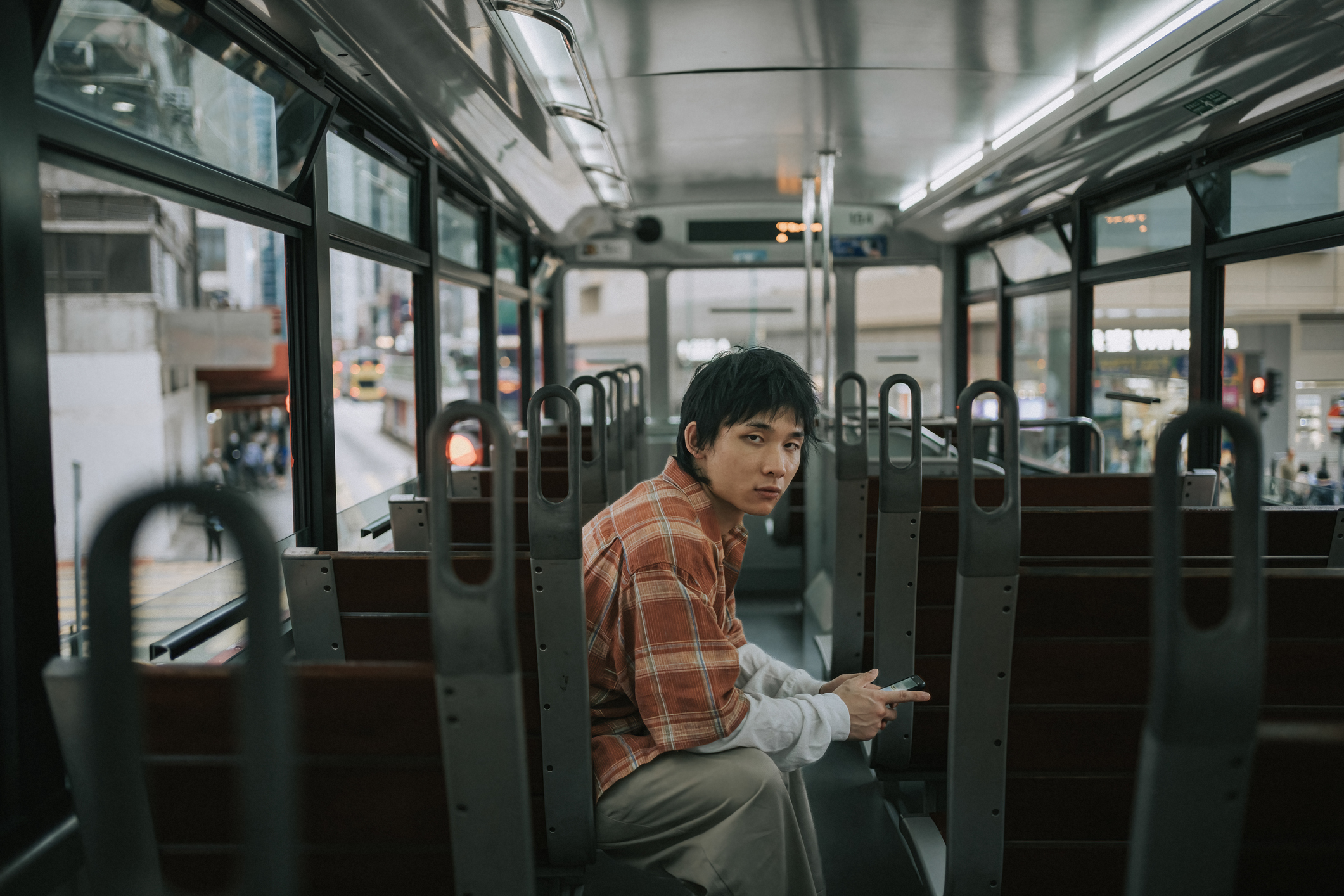 Young man sitting alone on a bus, symbolizing isolation and reflection after cutting ties with parents.