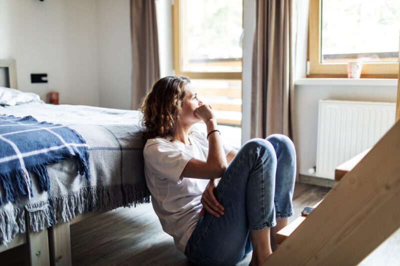 Woman sitting on floor, deep in thought, reflecting on self-identity and the impact of introjected beliefs.