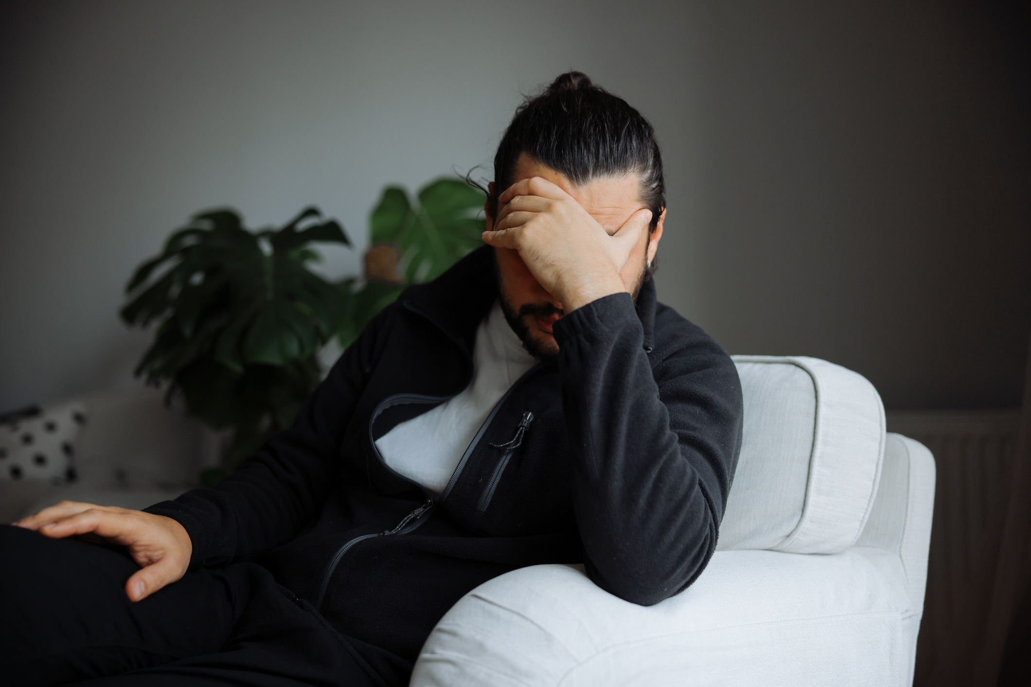 Man sitting with head in hand, illustrating emotional distress linked to mania or psychosis.