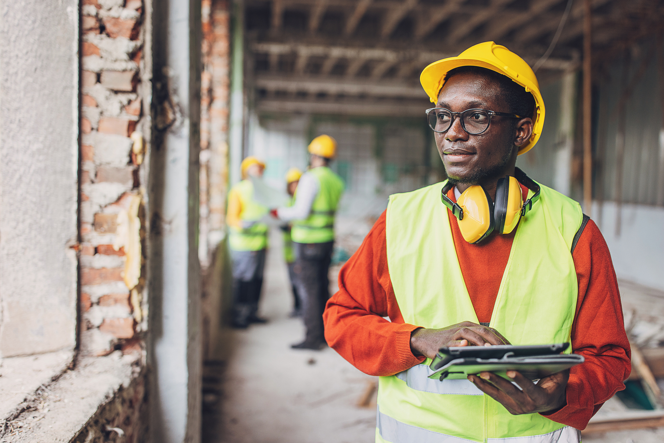 Construction worker with hard hat and tablet, showing resilience in managing mental health at work.