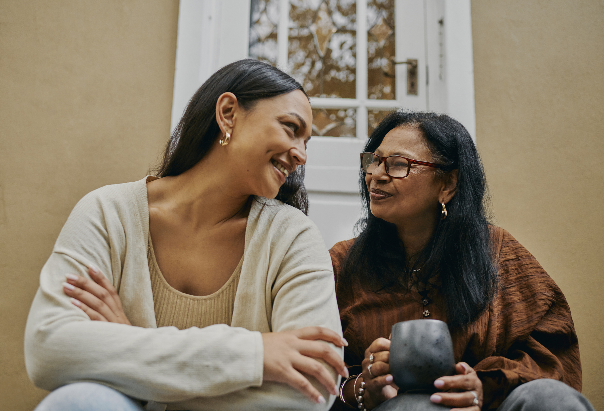 Two women sharing a warm, supportive moment on a doorstep—symbolizing generational connection and open conversation, relevant to exploring genetic and familial links in eating disorders.