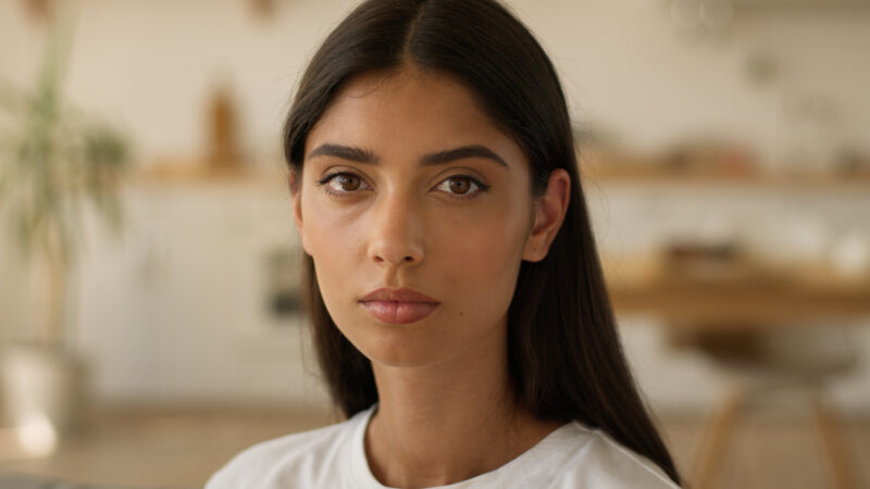 Young woman with a serious expression, symbolizing the emotional impact of mental health stigma, as explored in research on the real effects of stigma.