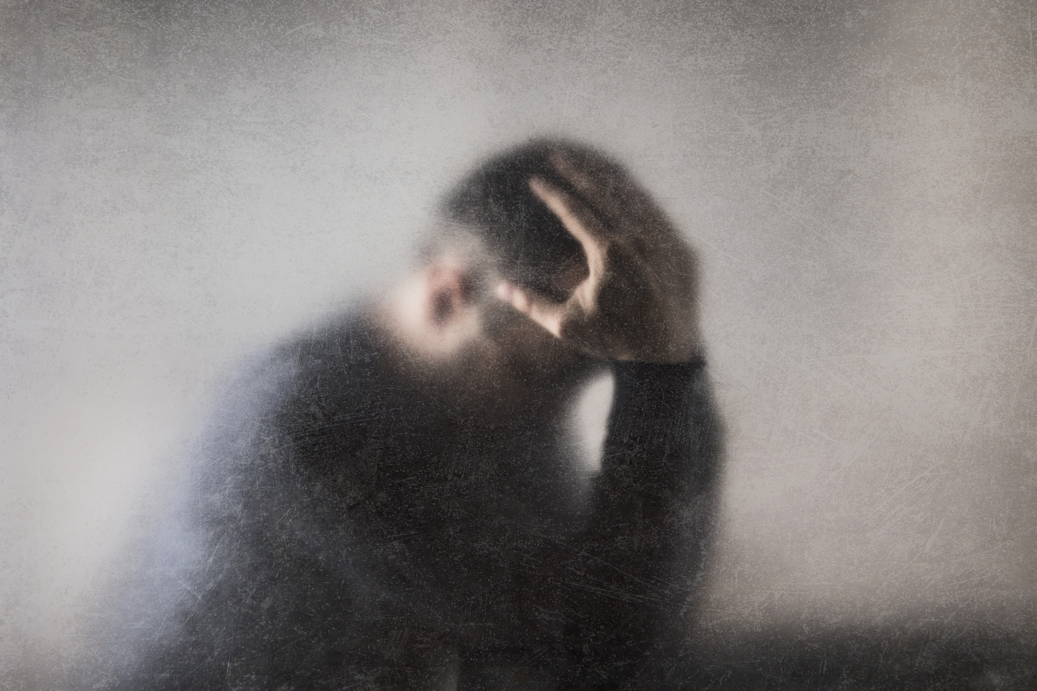 Blurry image of a man holding his head in distress, conveying intense emotional pain or mental fog commonly associated with major depressive episodes.