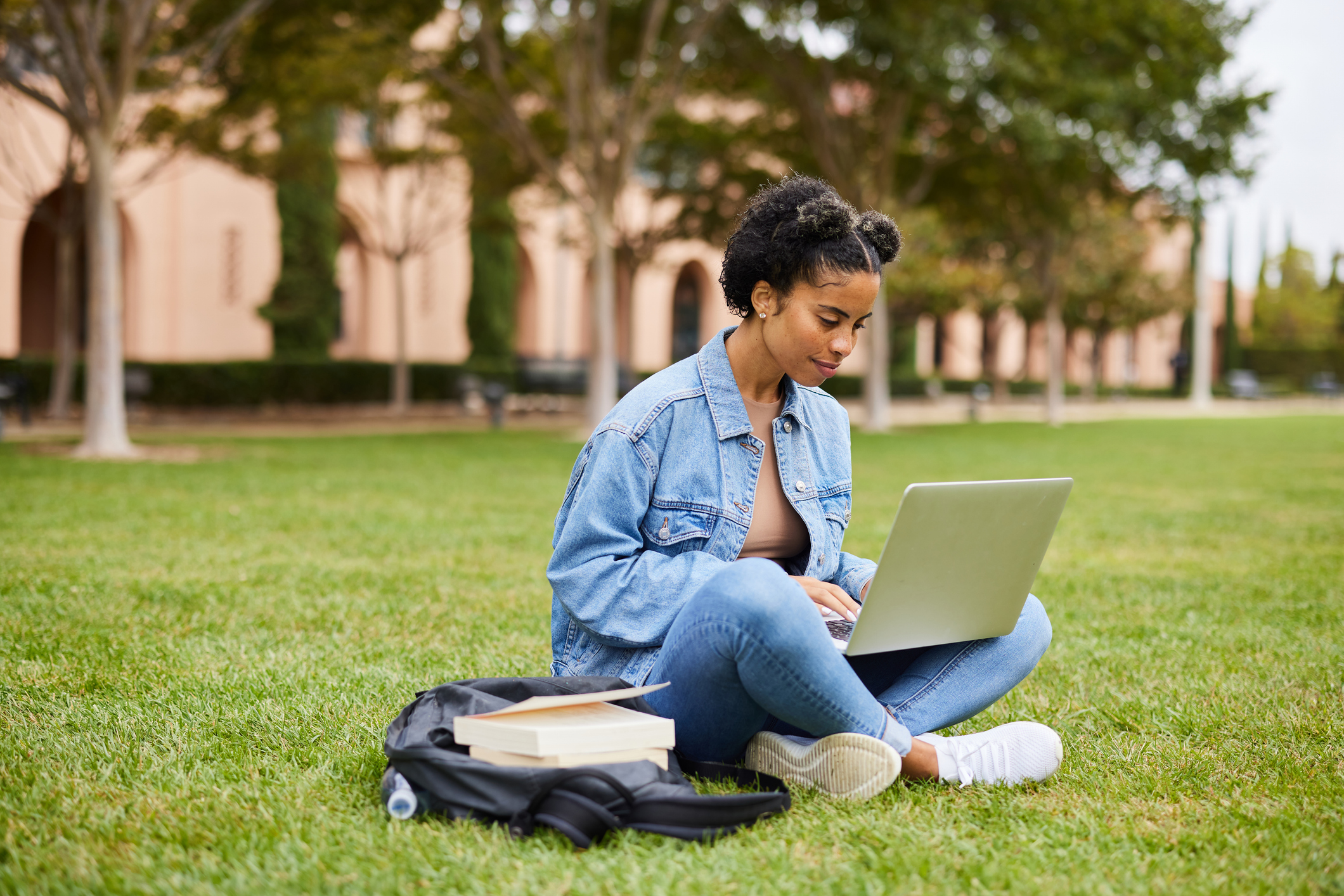 Young woman studying on a college campus lawn, symbolizing early intervention and education as key components in addressing alcohol abuse and accessing treatment resources.
