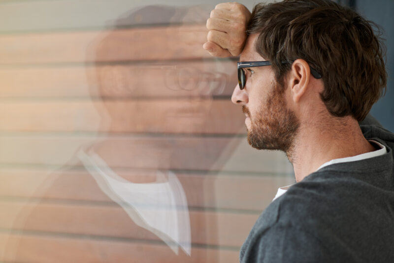 Man wearing glasses, resting his forehead on his hand with a blurred overlay, symbolizing the ongoing mental exhaustion and fog often experienced with chronic depression.