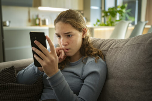 A child relaxes on the grass with headphones on, representing healthy coping strategies for managing school-related anxiety.