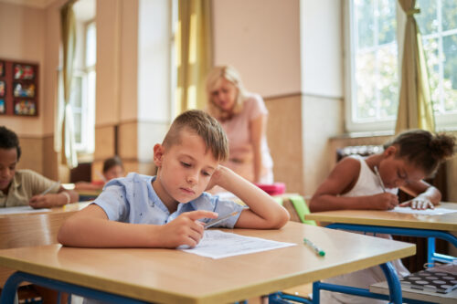 Young boy with ADHD concentrating on schoolwork in classroom, showing strategies to improve focus and learning support.