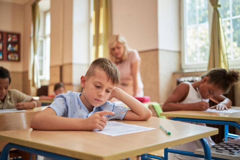 Young boy with ADHD concentrating on schoolwork in classroom, showing strategies to improve focus and learning support.