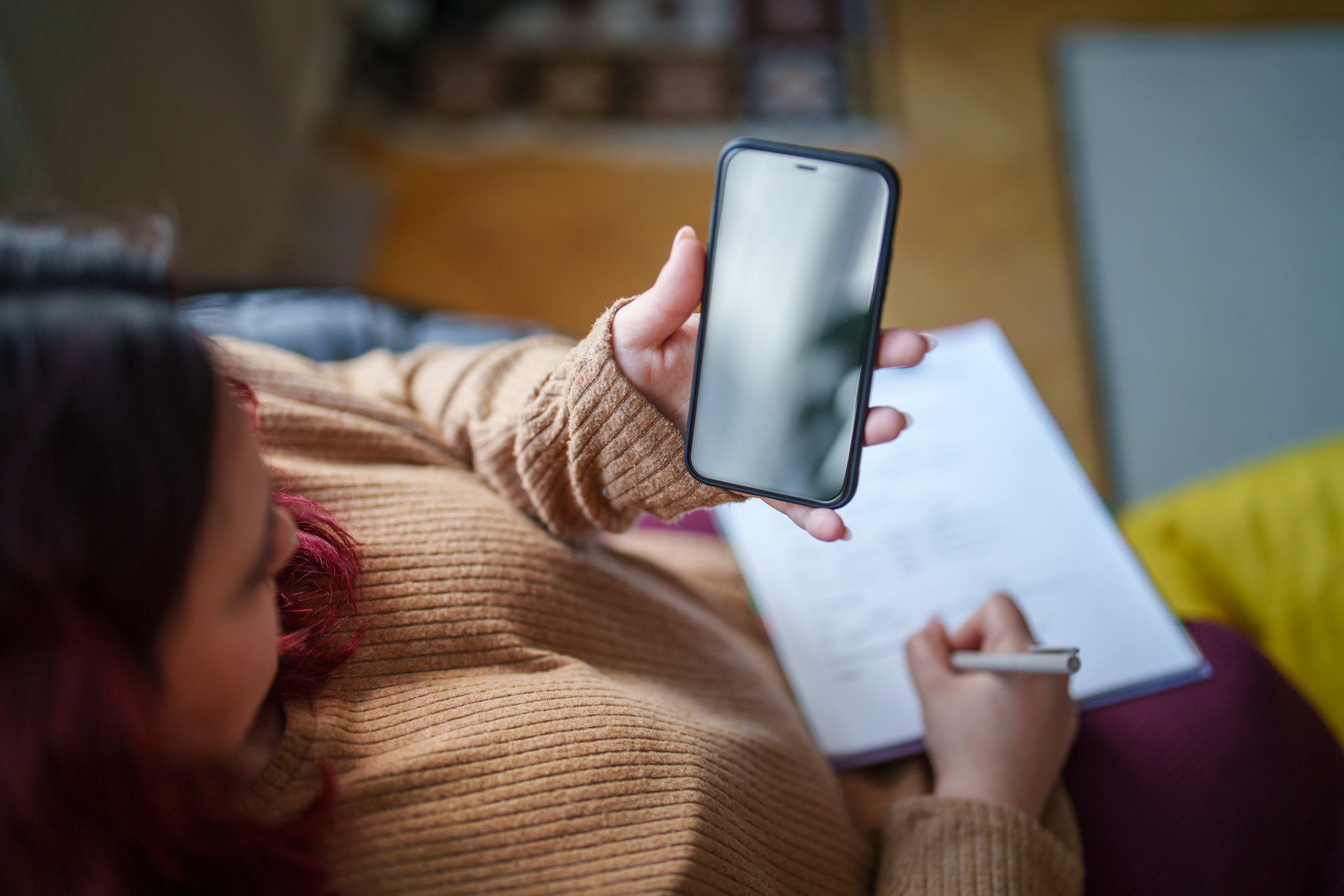 Individual using self-harm tracker app alongside journaling to aid recovery and emotional well-being.