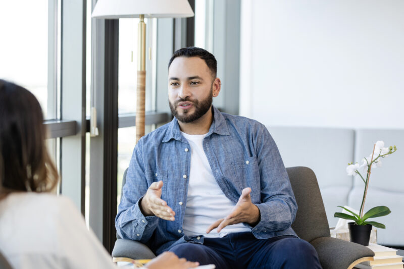 A young man gestures as he shares something during a Charlie Health therapy session.
