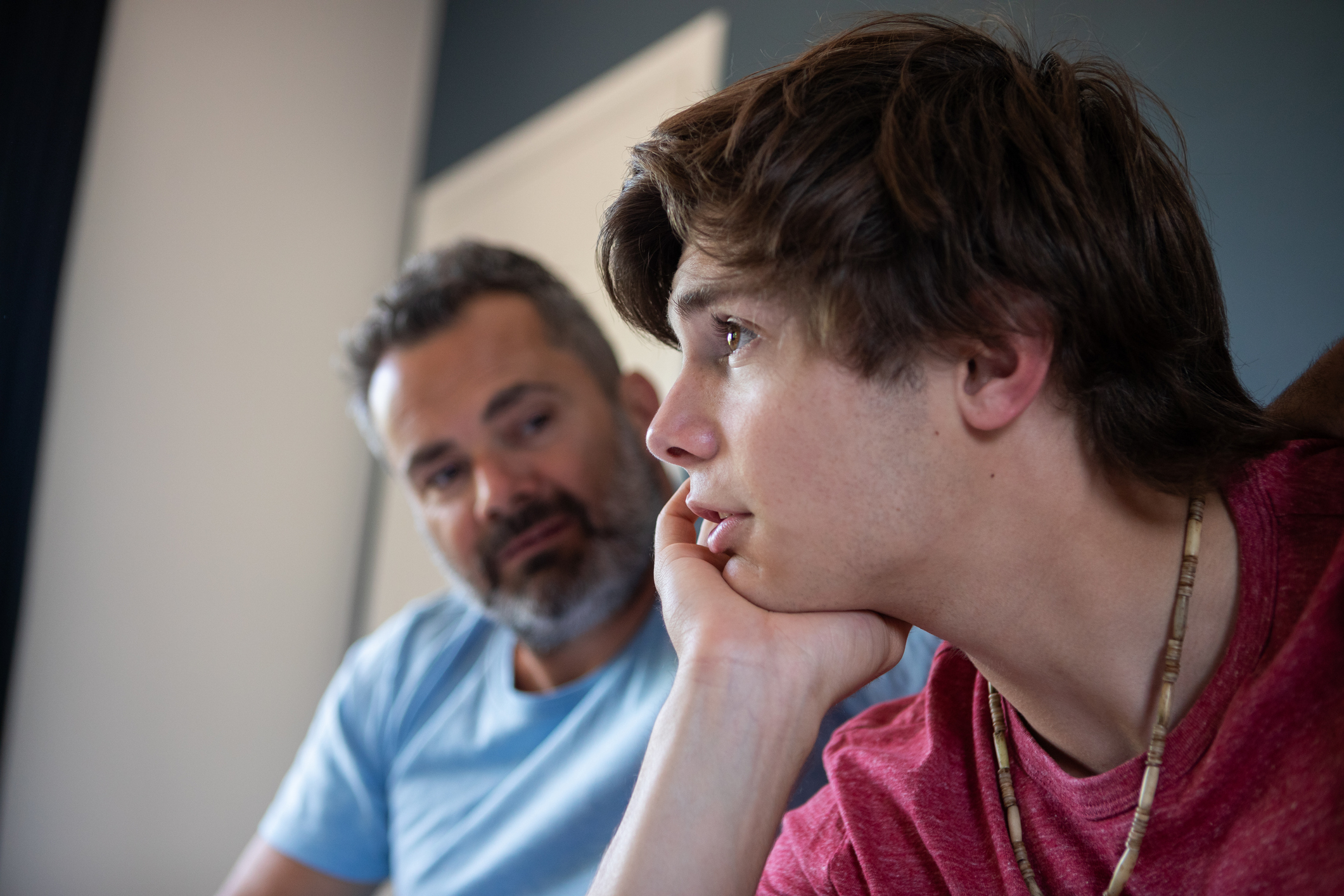 Father looking happily at son who is talking about his emotions, and displaying signs of healing from his intensive therapy.
