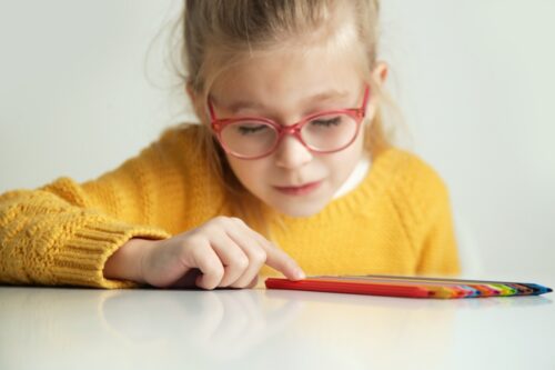 Young girl wearing glasses struggles to count colored pencils due to OCD.